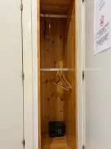 Baño con ducha acristalada, inodoro, secador de pared y lavabo con mueble blanco